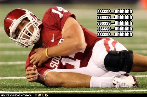 Oklahoma quarterback Sam Bradford  lays on the turf grabbing his shoulder in pain. Text on image repeats 
