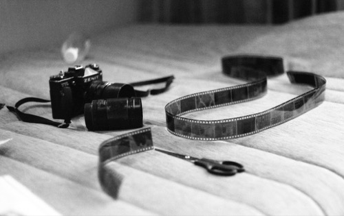 A film camera, film strip, and scissors on a surface