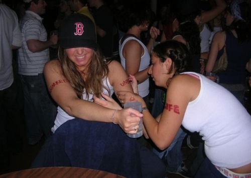 One woman writing on the arm of another while the first woman winces. The caption on the site where the image was found: 