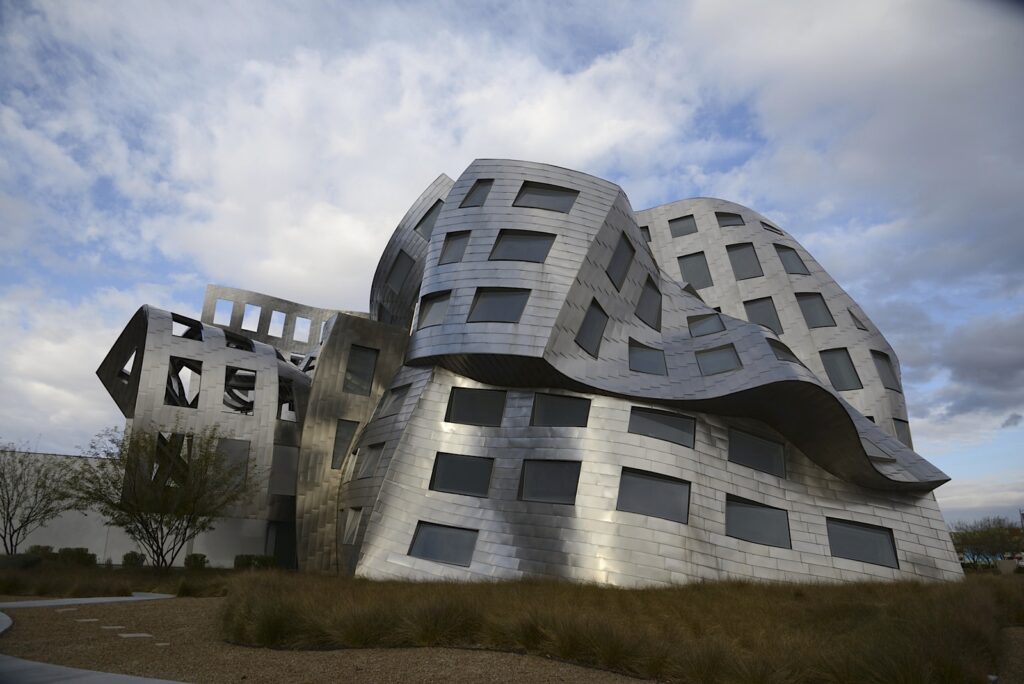 The exterior of the Lou Ruovo Center for Brain Health, in Las Vegas, Nevada. The metal exterior is warped and wavy. The entire building is folding in on itself as it defies the rules of gravity and modern architecture.